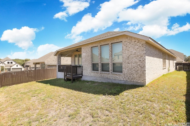 back of property with a yard and ceiling fan