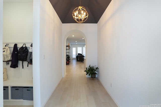 hallway featuring light hardwood / wood-style flooring, a chandelier, and vaulted ceiling