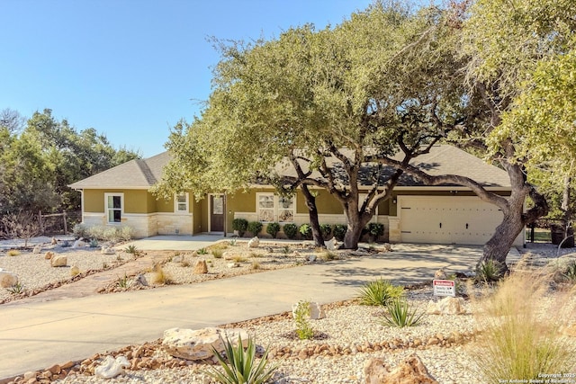 view of front of house featuring a garage, stone siding, driveway, and stucco siding