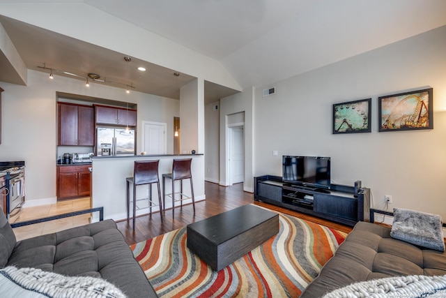 living room featuring lofted ceiling and light hardwood / wood-style floors