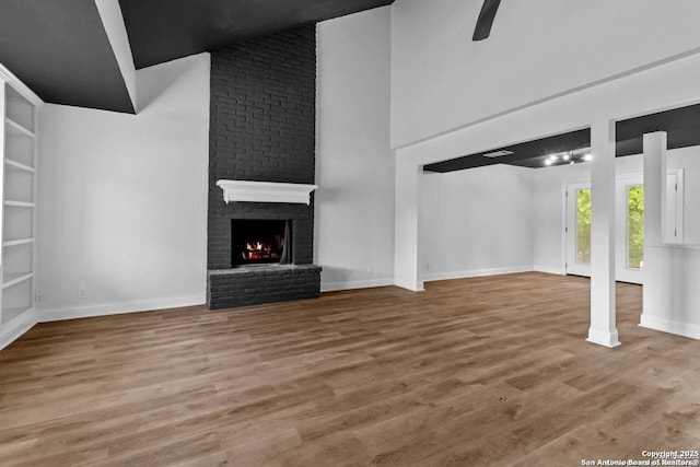 unfurnished living room with a fireplace, wood-type flooring, and ceiling fan