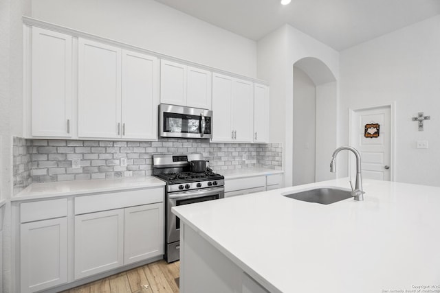 kitchen with backsplash, stainless steel appliances, sink, light hardwood / wood-style flooring, and white cabinetry