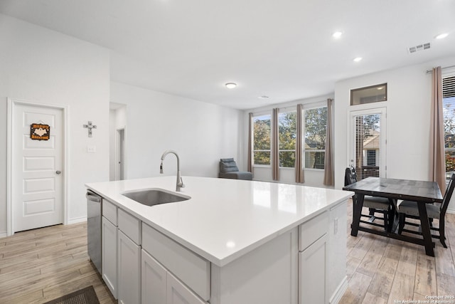 kitchen featuring white cabinetry, a kitchen island with sink, sink, and stainless steel dishwasher