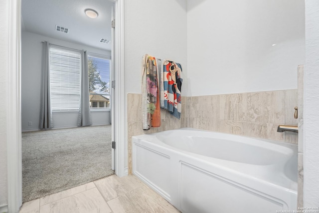 bathroom with a washtub and tile patterned flooring