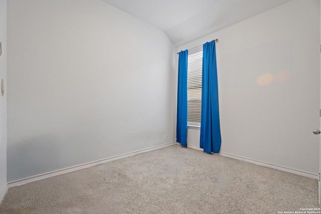 carpeted spare room with vaulted ceiling