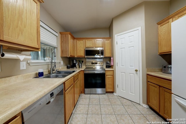 kitchen featuring appliances with stainless steel finishes, light tile patterned floors, lofted ceiling, and sink