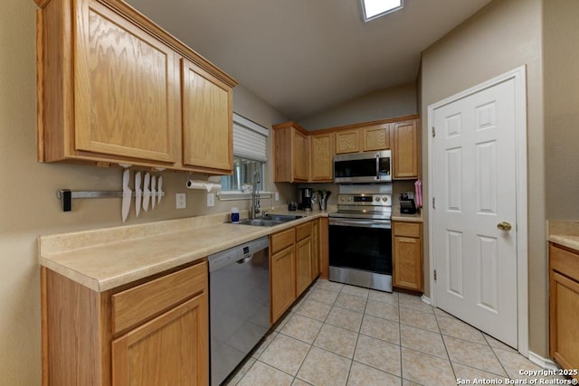 kitchen featuring appliances with stainless steel finishes, light tile patterned floors, vaulted ceiling, and sink