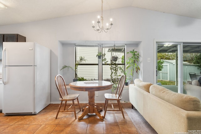 dining area with tile patterned floors, lofted ceiling, and a chandelier