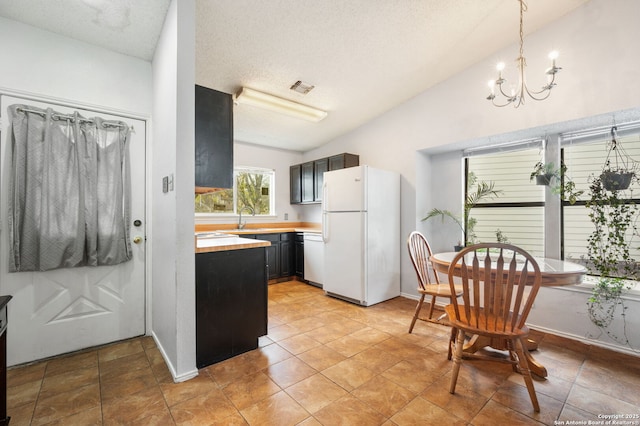 kitchen featuring sink, a chandelier, vaulted ceiling, a textured ceiling, and white appliances