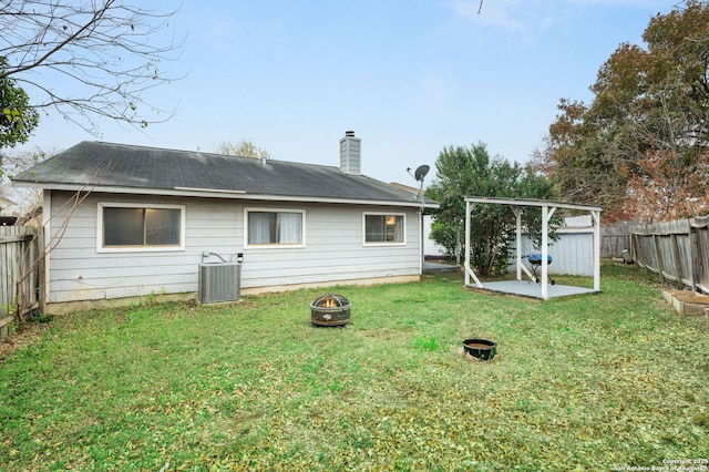 back of house with a fire pit, cooling unit, and a yard