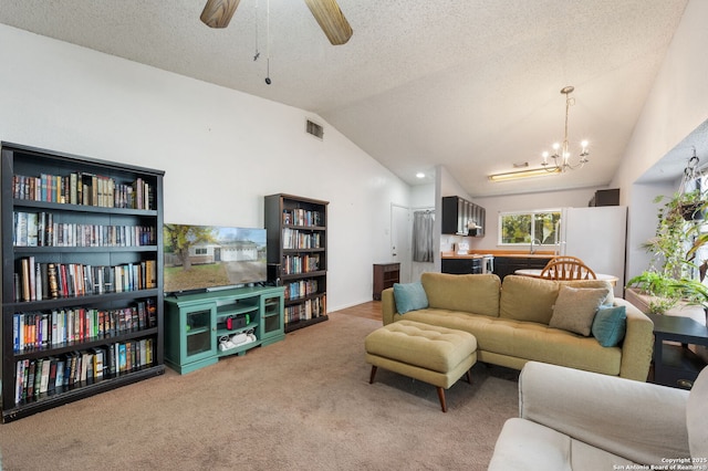 carpeted living room featuring ceiling fan with notable chandelier, a textured ceiling, lofted ceiling, and sink