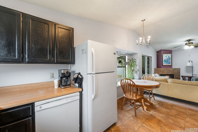 kitchen featuring a tile fireplace, vaulted ceiling, a textured ceiling, white appliances, and ceiling fan with notable chandelier