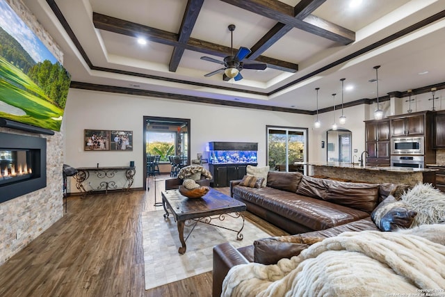 living room featuring ceiling fan, coffered ceiling, beamed ceiling, hardwood / wood-style floors, and ornamental molding