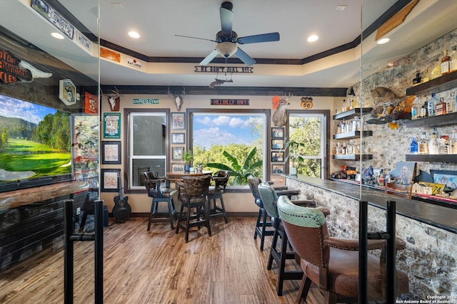 bar featuring hardwood / wood-style flooring, a raised ceiling, ceiling fan, and crown molding