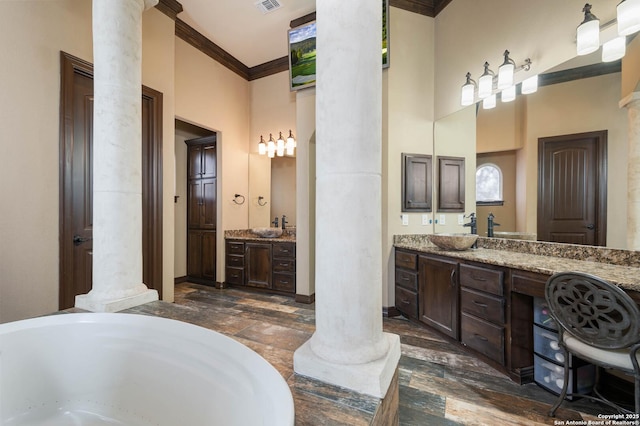 bathroom with ornate columns, vanity, and ornamental molding