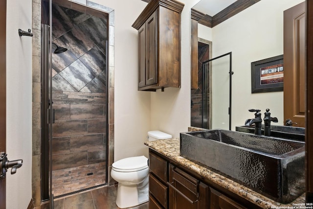 bathroom featuring vanity, toilet, an enclosed shower, and crown molding