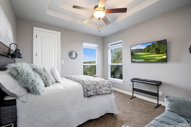 carpeted bedroom with a tray ceiling and ceiling fan