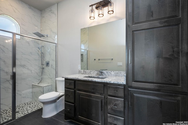 bathroom with a shower with door, vanity, and toilet