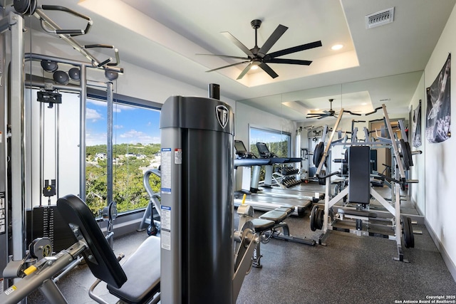 workout area featuring a tray ceiling and ceiling fan