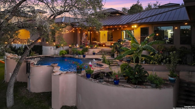 pool at dusk with a patio area