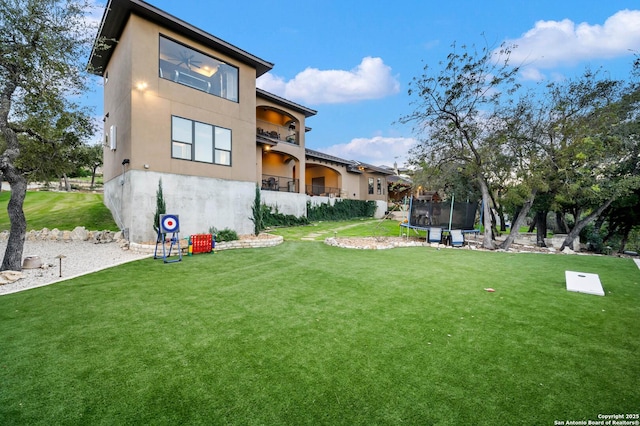 back of property featuring a yard and a trampoline