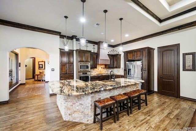 kitchen with a breakfast bar, hanging light fixtures, ornamental molding, a large island, and stainless steel appliances