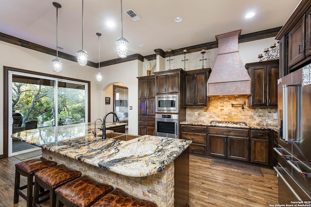 kitchen featuring custom exhaust hood, sink, decorative light fixtures, a large island, and stainless steel appliances