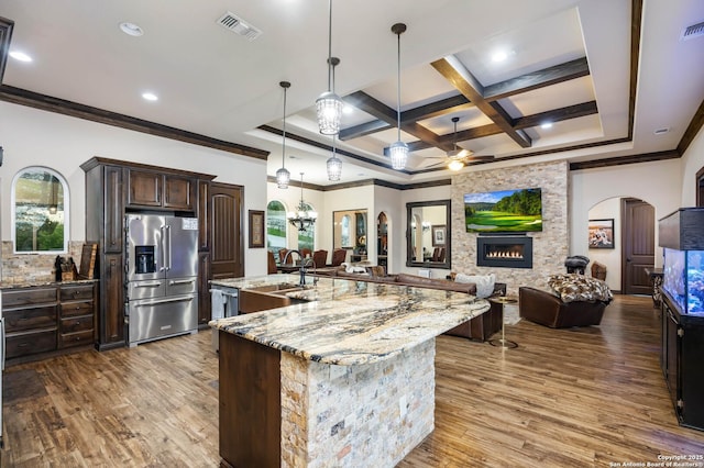 kitchen featuring high end refrigerator, coffered ceiling, a spacious island, a fireplace, and hanging light fixtures