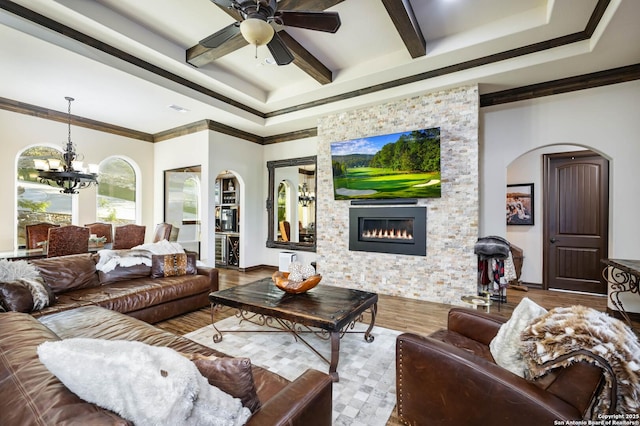 living room with a fireplace, wood-type flooring, ceiling fan with notable chandelier, and ornamental molding