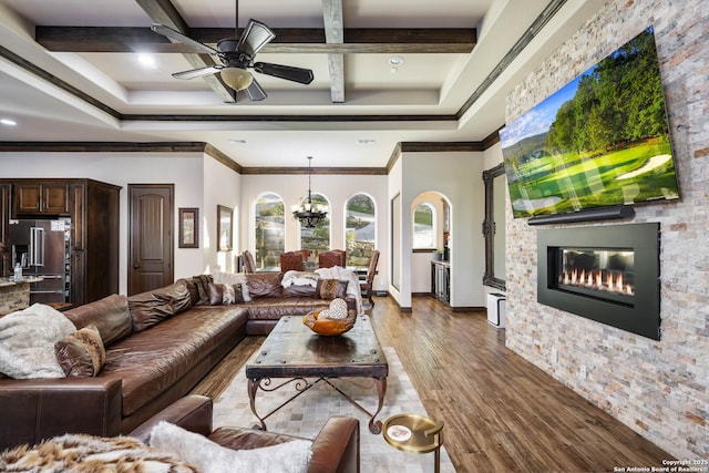 living room featuring coffered ceiling, ceiling fan with notable chandelier, crown molding, beam ceiling, and hardwood / wood-style flooring