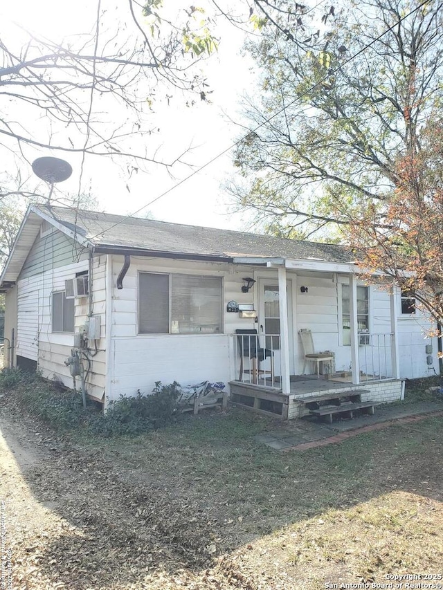 view of front facade with a wall mounted AC and a porch