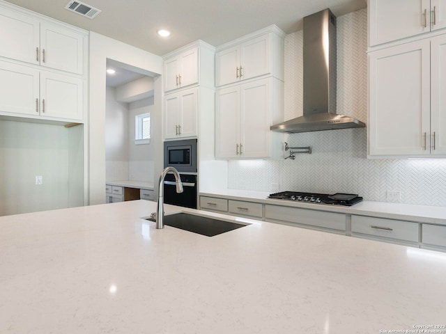 kitchen with sink, wall chimney exhaust hood, decorative backsplash, white cabinetry, and stainless steel appliances