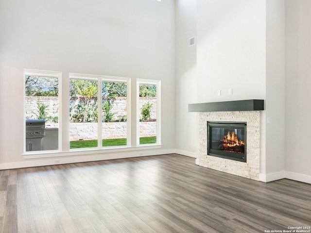 unfurnished living room featuring a fireplace, a high ceiling, and hardwood / wood-style flooring