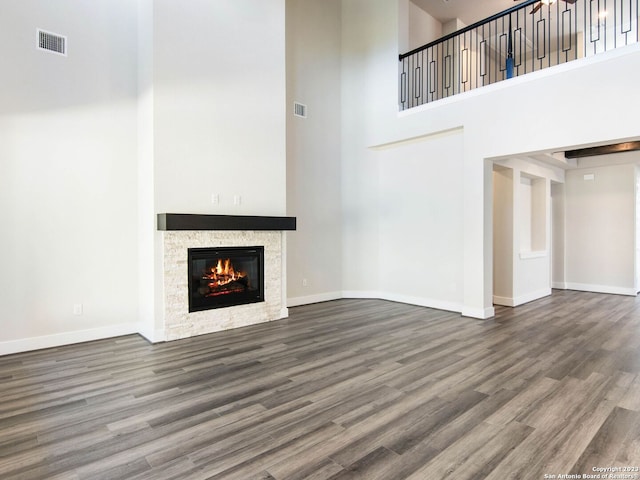 unfurnished living room with a towering ceiling and wood-type flooring