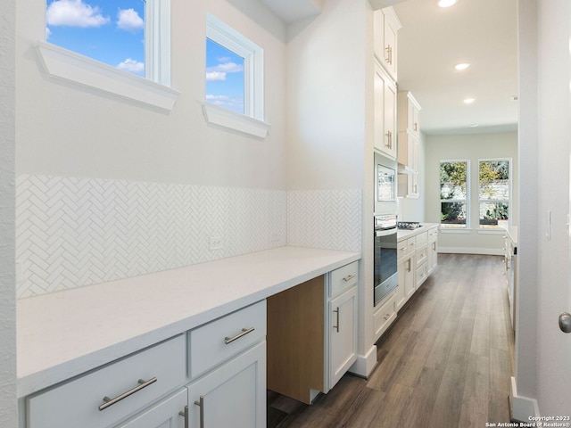 kitchen featuring white cabinetry, built in microwave, dark hardwood / wood-style floors, oven, and decorative backsplash