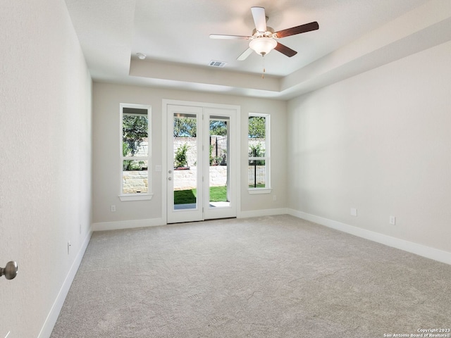 spare room with a tray ceiling, ceiling fan, and light colored carpet