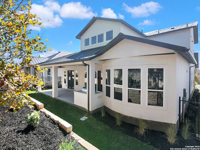 rear view of house featuring ceiling fan and a patio area