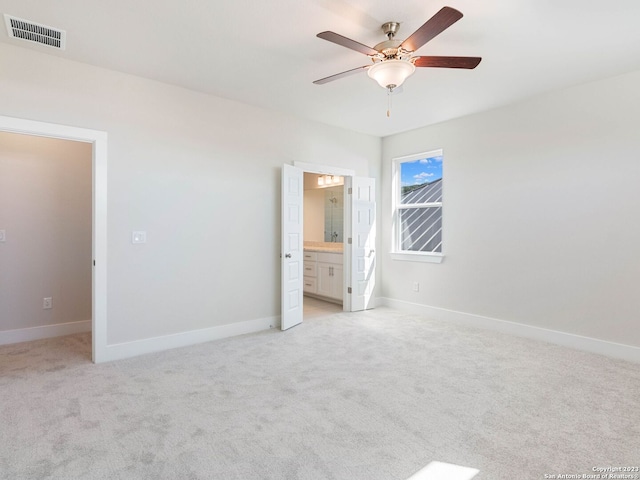 unfurnished bedroom featuring ceiling fan, light carpet, and connected bathroom