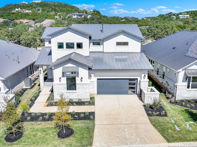 view of front of home featuring cooling unit, a garage, and a front lawn