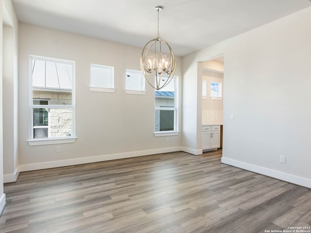 unfurnished room with a chandelier and light wood-type flooring