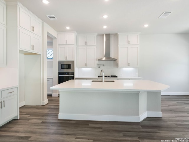 kitchen with white cabinetry, a center island with sink, wall chimney exhaust hood, and stainless steel appliances