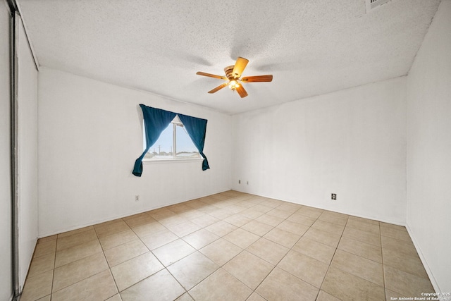 spare room with ceiling fan, light tile patterned floors, and a textured ceiling