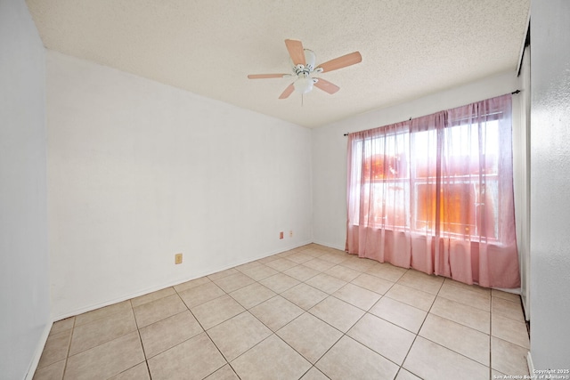 empty room featuring ceiling fan, light tile patterned flooring, and a textured ceiling