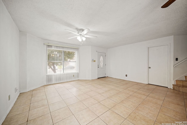 spare room featuring ceiling fan, light tile patterned flooring, and a textured ceiling