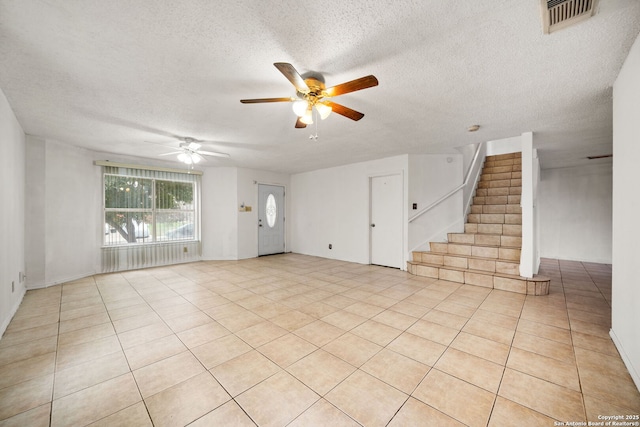 unfurnished living room with ceiling fan, light tile patterned floors, and a textured ceiling