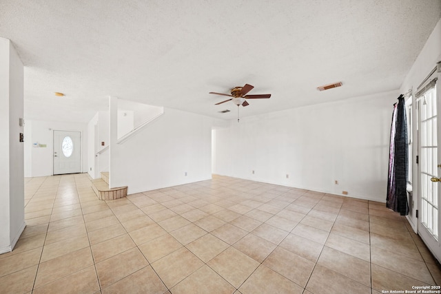 unfurnished room featuring ceiling fan, light tile patterned flooring, and a textured ceiling