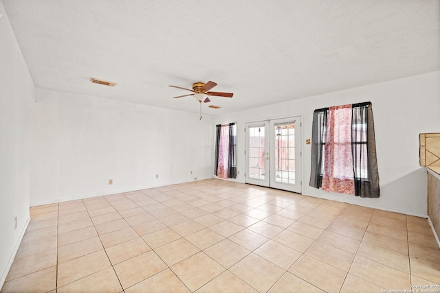 tiled empty room with ceiling fan, french doors, and a textured ceiling