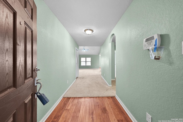 hall with a textured ceiling and hardwood / wood-style flooring