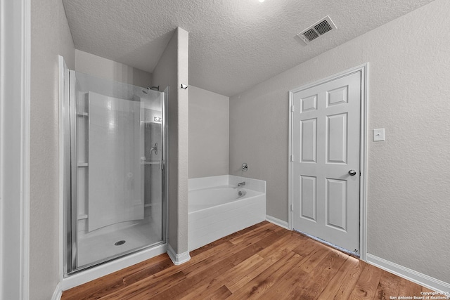 bathroom featuring hardwood / wood-style floors, a textured ceiling, and independent shower and bath