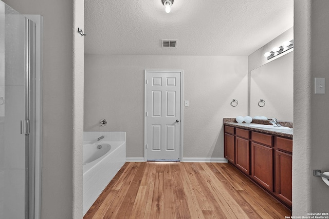 bathroom with vanity, a bathtub, wood-type flooring, and a textured ceiling